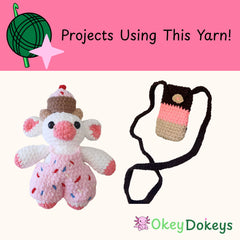 Crocheted items including a pink cow and a p[hone with yarn on a pink background, featuring Okey Dokeys branding.