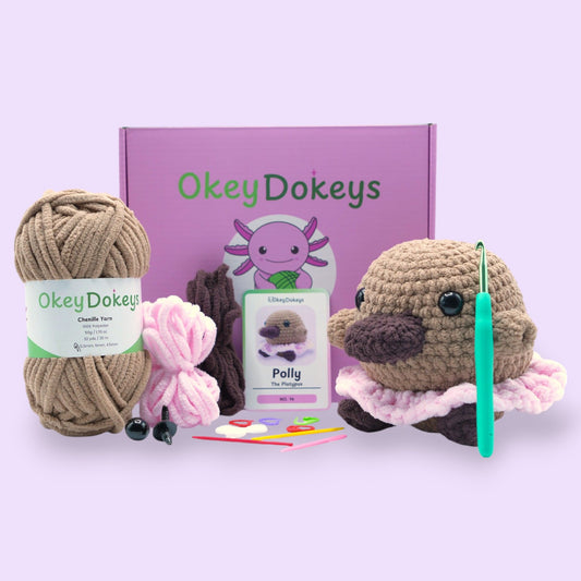 A crochet kit including a plush toy shaped like a platypus, with yarn in various colors and a crochet hook.