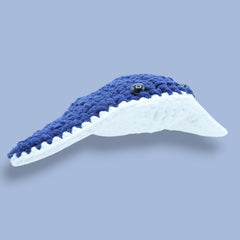 Crocheted blue and white stingray toy on a purple background