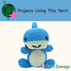 Crocheted blue and white creature with 'Okey Dokeys' branding on a white background