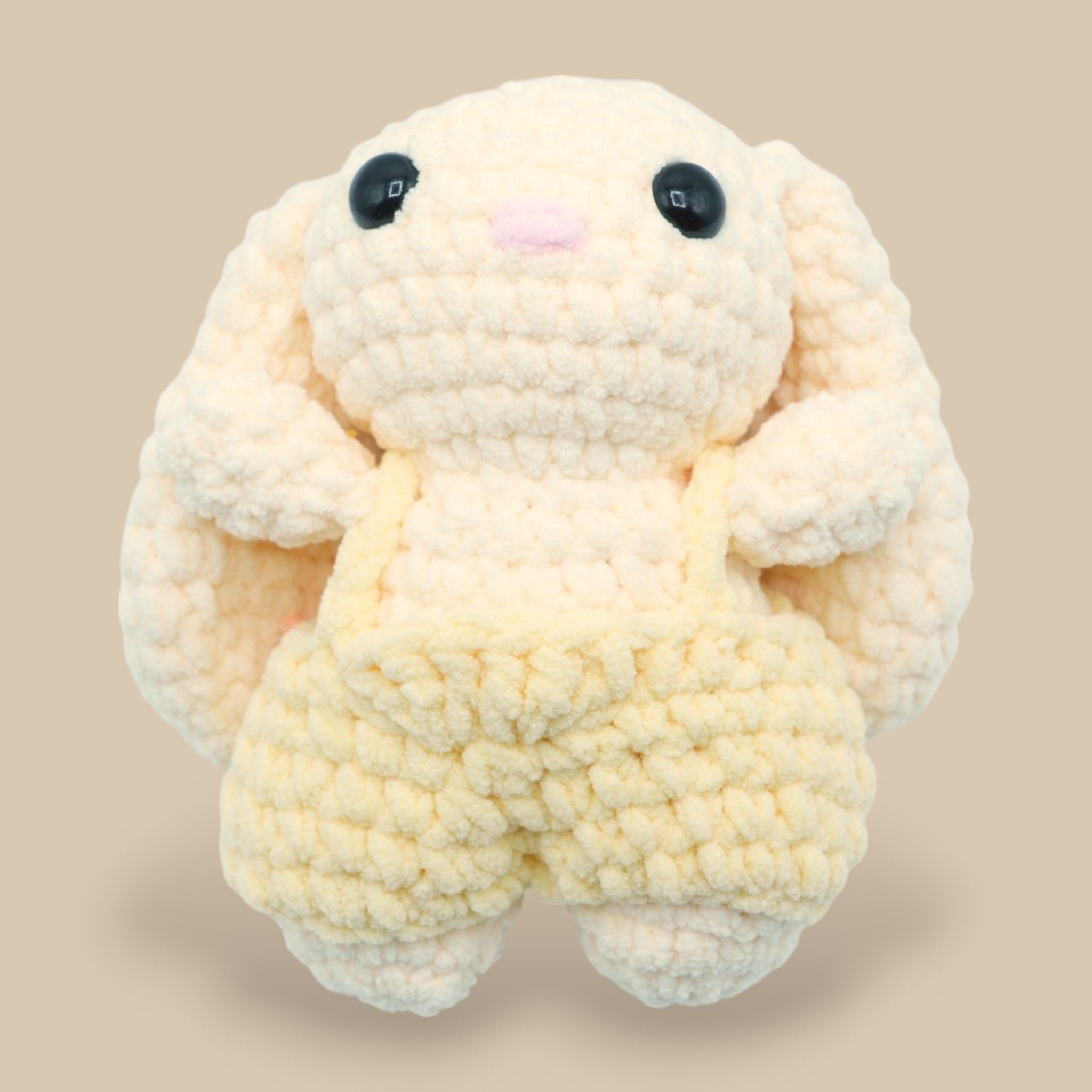 A crochet bunny kit with yarn in yellow and pink, a crochet hook, safety eyes, a stuffing needle, stitch markers, scissors, and a pattern booklet, all presented with a 'Okey Dokey' branded box.