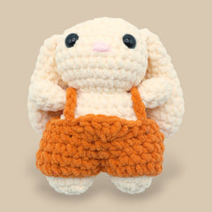 A crochet bunny kit with yarn in yellow and pink, a crochet hook, safety eyes, a stuffing needle, stitch markers, scissors, and a pattern booklet, all presented with a 'Okey Dokey' branded box.