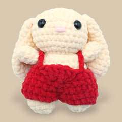 A crochet bunny kit with yarn in yellow and pink, a crochet hook, safety eyes, a stuffing needle, stitch markers, scissors, and a pattern booklet, all presented with a 'Okey Dokey' branded box.