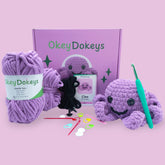 A crochet octopus kit by OkeyDokey, including purple chenille yarn, a crochet hook, safety eyes, stuffing needle, stitch markers, and a pattern booklet, alongside the completed purple octopus plush.