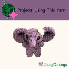 Crocheted purple elephant toy with a white flower on a white background, featuring Okey Dokeys branding.