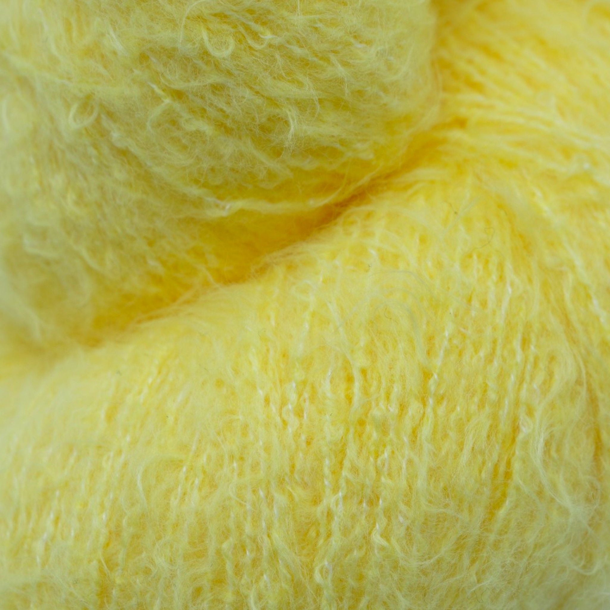 A skein of fuzzy lace yarn in a light yellow color, displayed against a plain background.