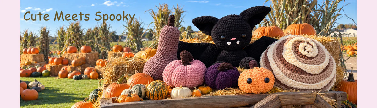 A crocheted black bat sits on a wooden crate filled with autumn decorations, including pumpkins, gourds, a pink pumpkin, a purple pumpkin, hay bales, and a brown-and-cream spiral hat, outdoors in a pumpkin field under a blue sky. The text 'Cute Meets Spooky' appears in the upper left.