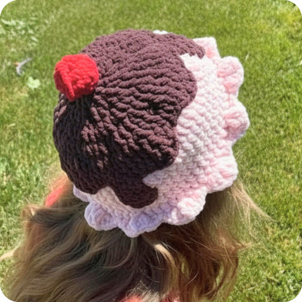 Crocheted hat with a red pom-pom on a grassy background