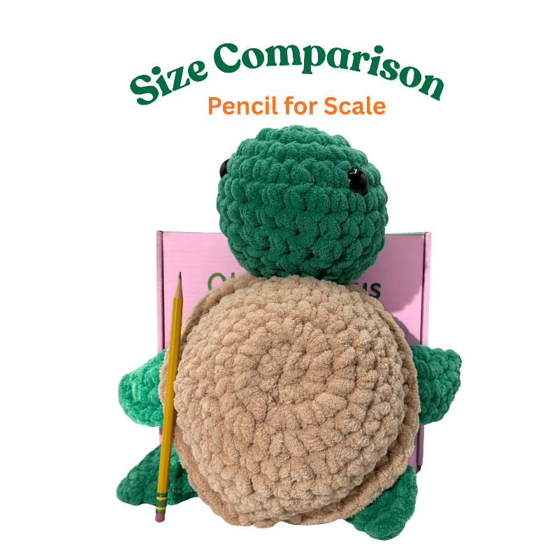Crocheted turtle toy with a pencil for scale on a white background