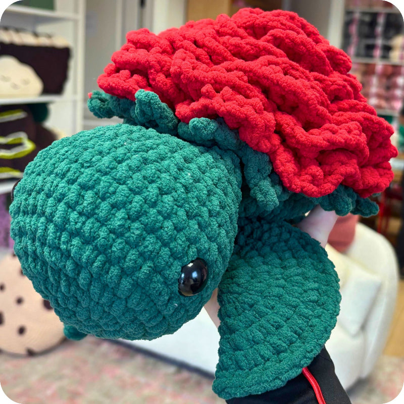Crocheted turtle with red shell in a store setting