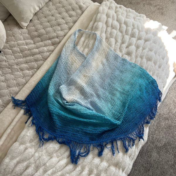 Blue and white woven blanket with fringes on a textured surface