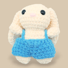 A crochet bunny kit with yarn in yellow and pink, a crochet hook, safety eyes, a stuffing needle, stitch markers, scissors, and a pattern booklet, all presented with a 'Okey Dokey' branded box.