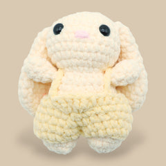 A crochet bunny kit with yarn in yellow and pink, a crochet hook, safety eyes, a stuffing needle, stitch markers, scissors, and a pattern booklet, all presented with a 'Okey Dokey' branded box.