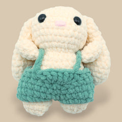 A crochet bunny kit with yarn in yellow and pink, a crochet hook, safety eyes, a stuffing needle, stitch markers, scissors, and a pattern booklet, all presented with a 'Okey Dokey' branded box.